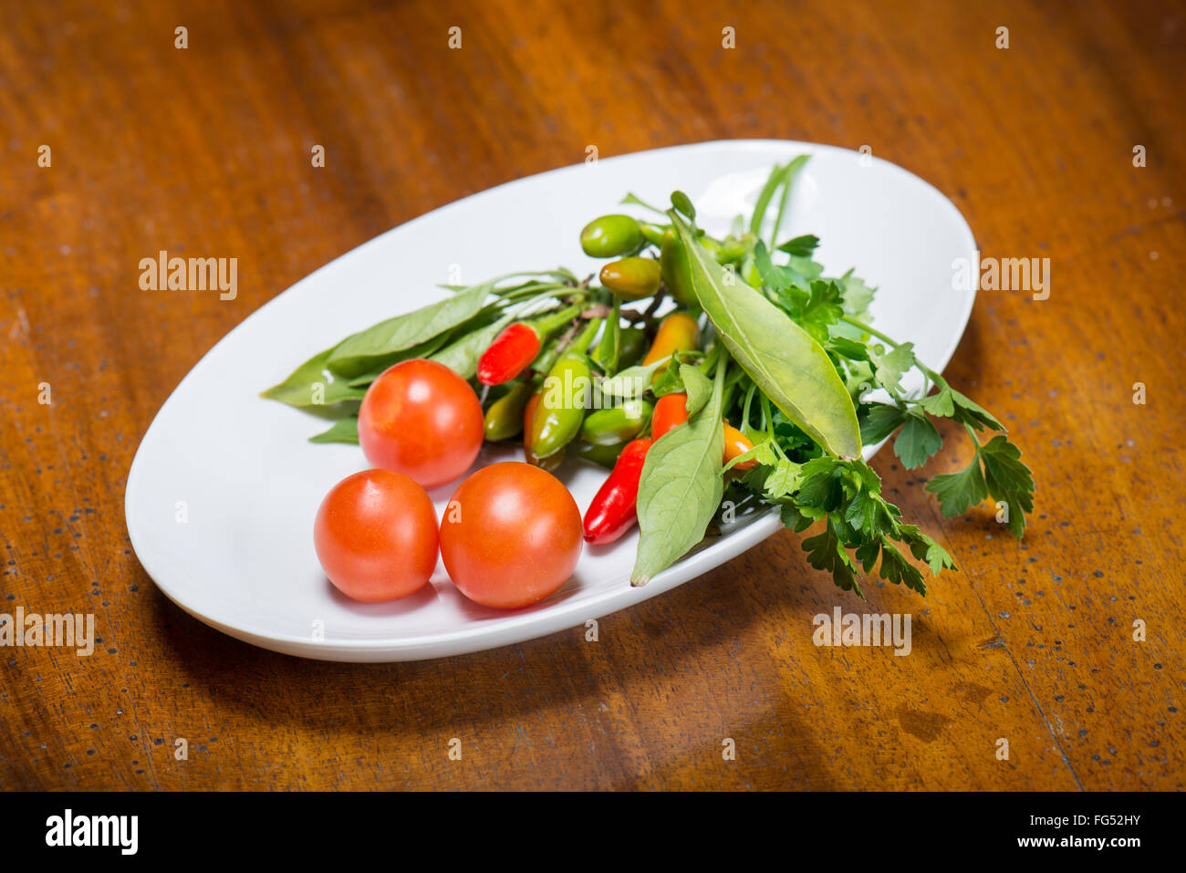 Tomates y pimientos picantes con perejil fresco del jardín Foto de stock