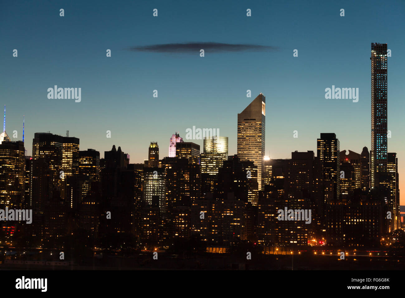Paisaje urbano de Manhattan con cielo despejado y una oscura nube plana durante el crepúsculo en la Ciudad de Nueva York. Foto de stock