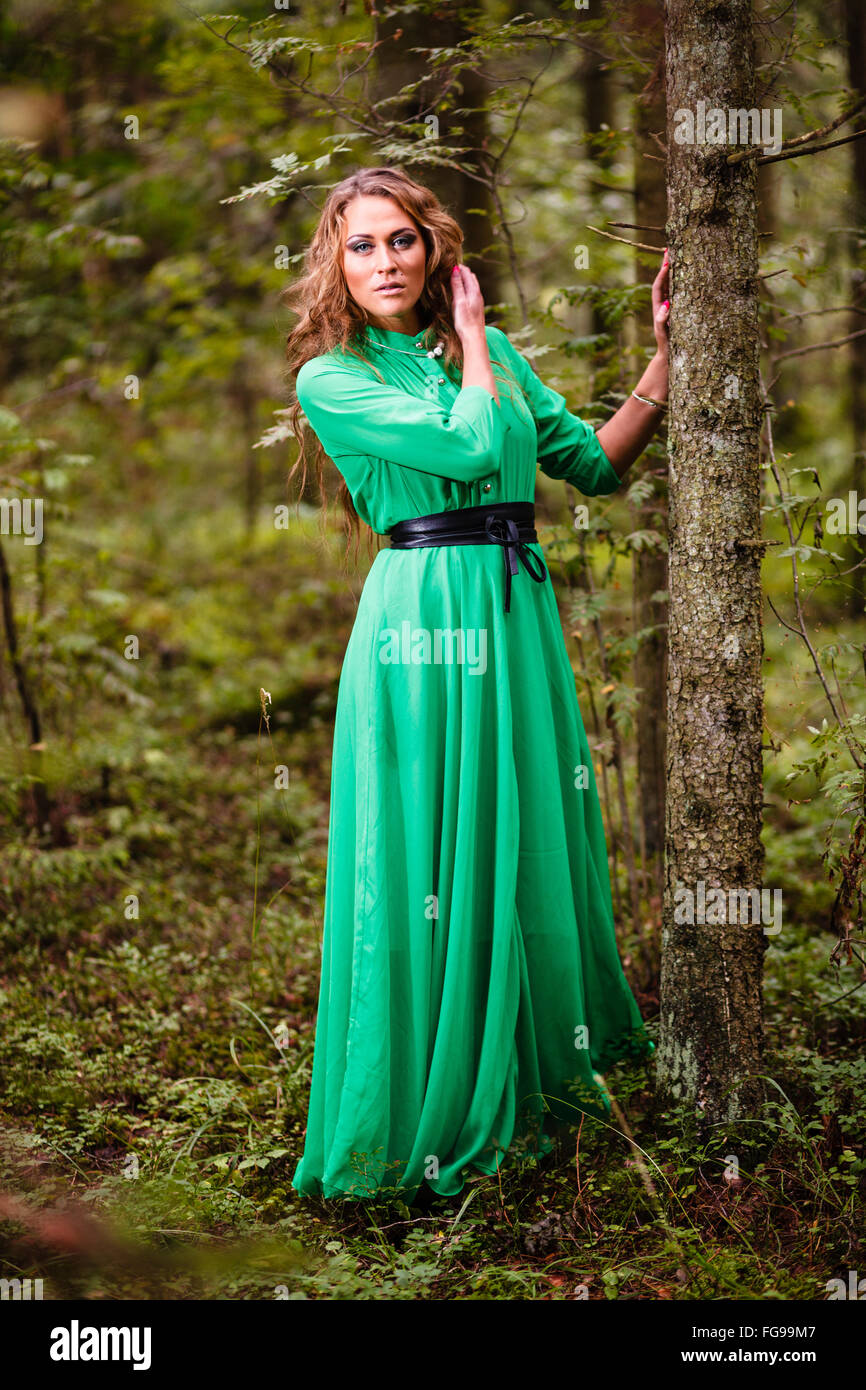 Niña de pelo largo vestido verde en el bosque. Foto de stock