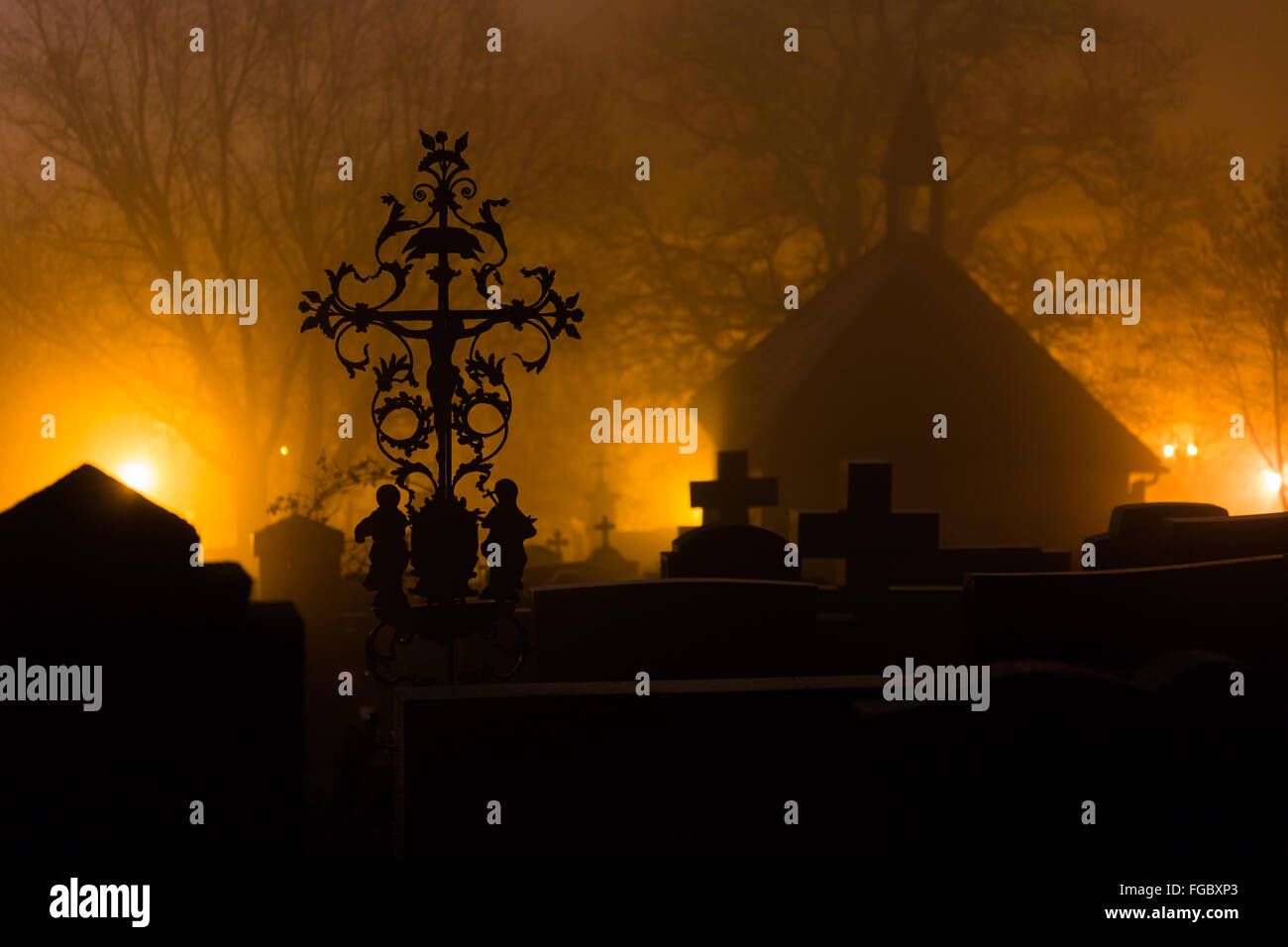 Silueta de cementerios en el cementerio contra los árboles durante la niebla por la noche Foto de stock