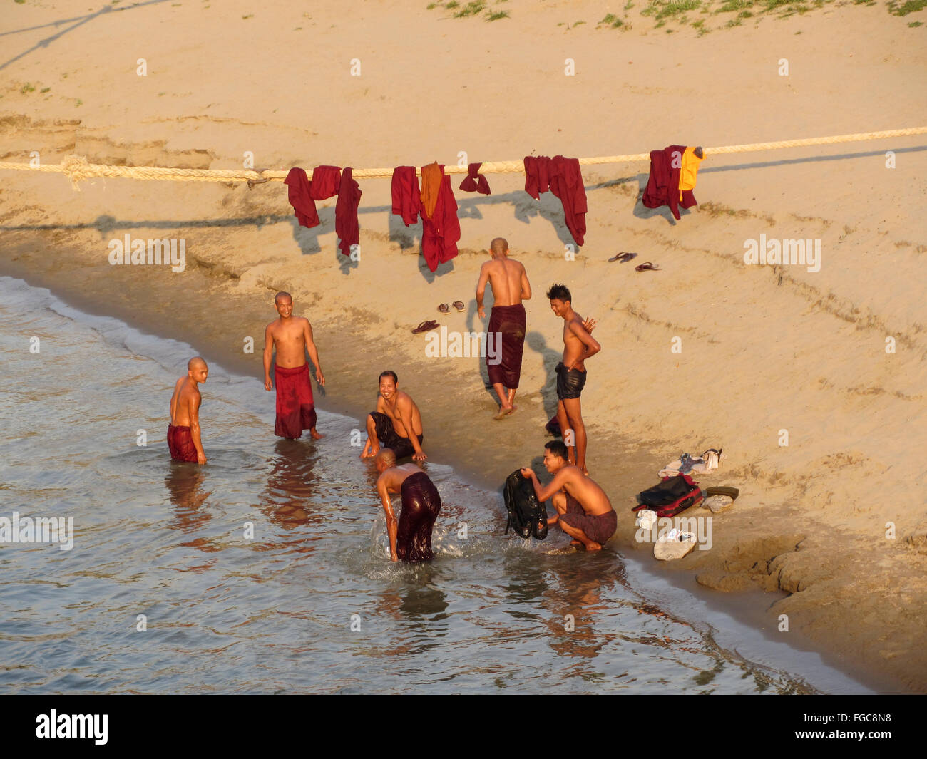 Grupo de machos adultos de monjes budistas bañándose y lavando su ropa en el río Irrawaddy bancos en el centro de Myanmar (Birmania). Foto de stock
