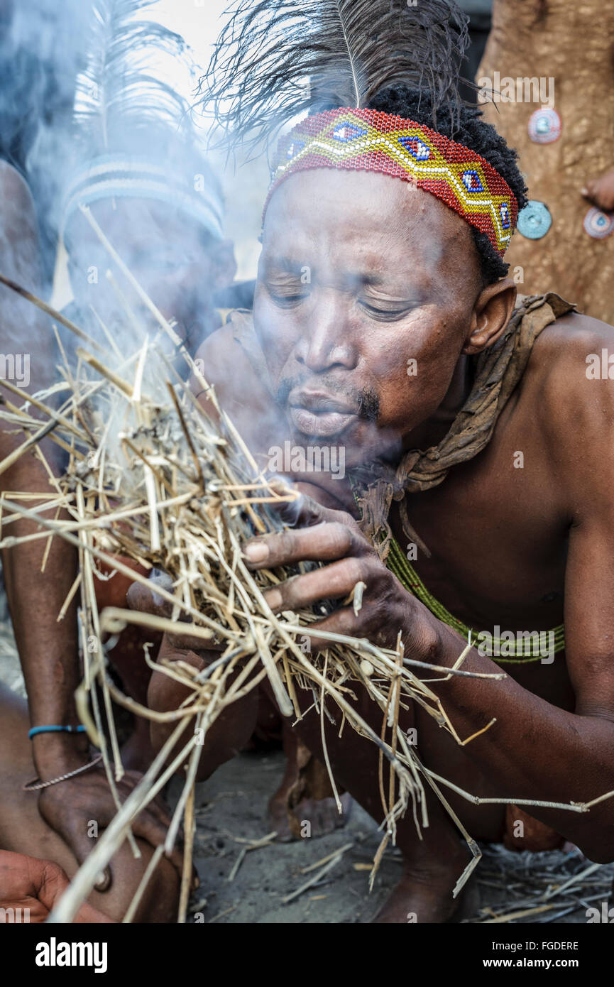 San Kalahari hombre soplando pajitas para hacer fuego a la manera tradicional. Foto de stock