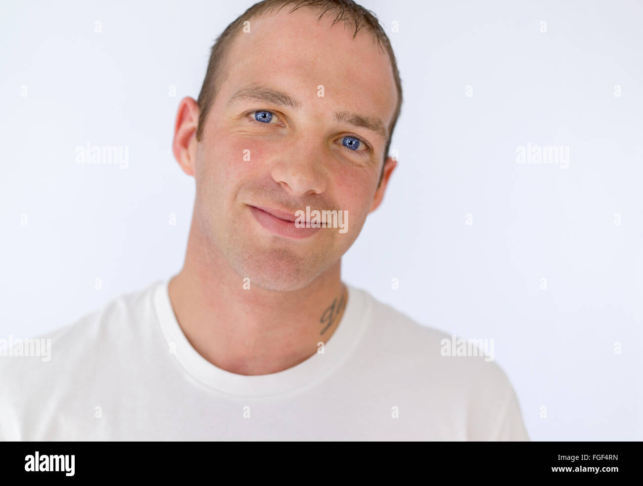 Retrato de un hombre que llevaba una camiseta blanca sonriente Foto de stock