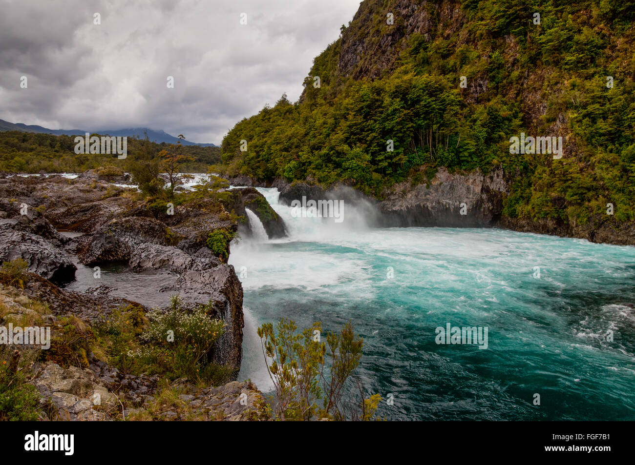 Río Petrohue con formaciones de roca volcánica y Volcán Osorno (fondo) en tiempo nublado, Chile. Foto de stock