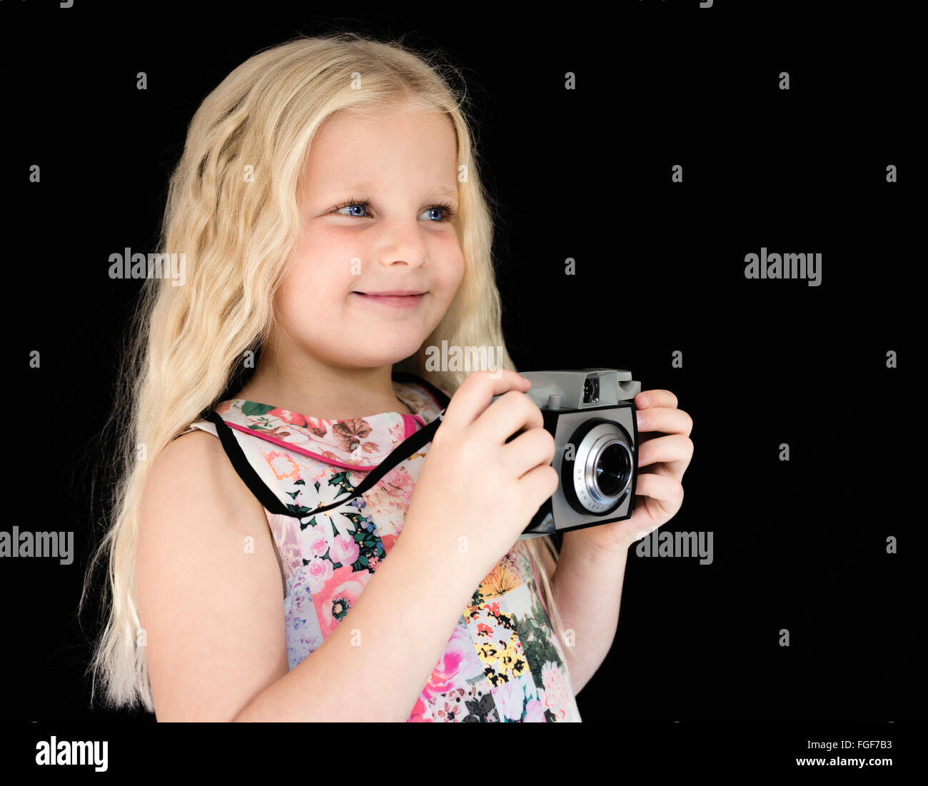Joven con largo pelo rubio sosteniendo una cámara vintage sonriendo Foto de stock
