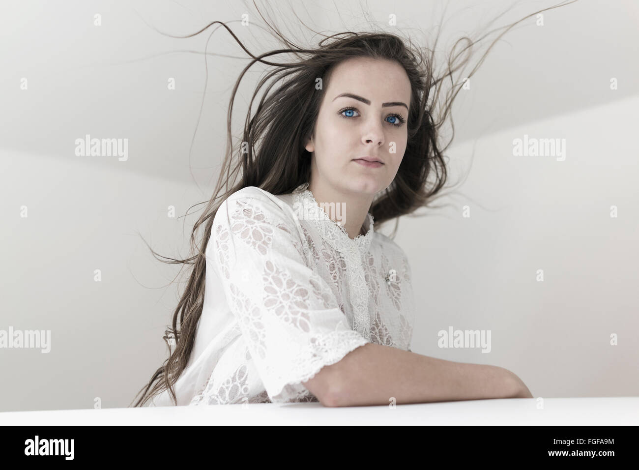 Mujer sentada en la mesa con el flyaway pelo y una grave expresión Foto de stock