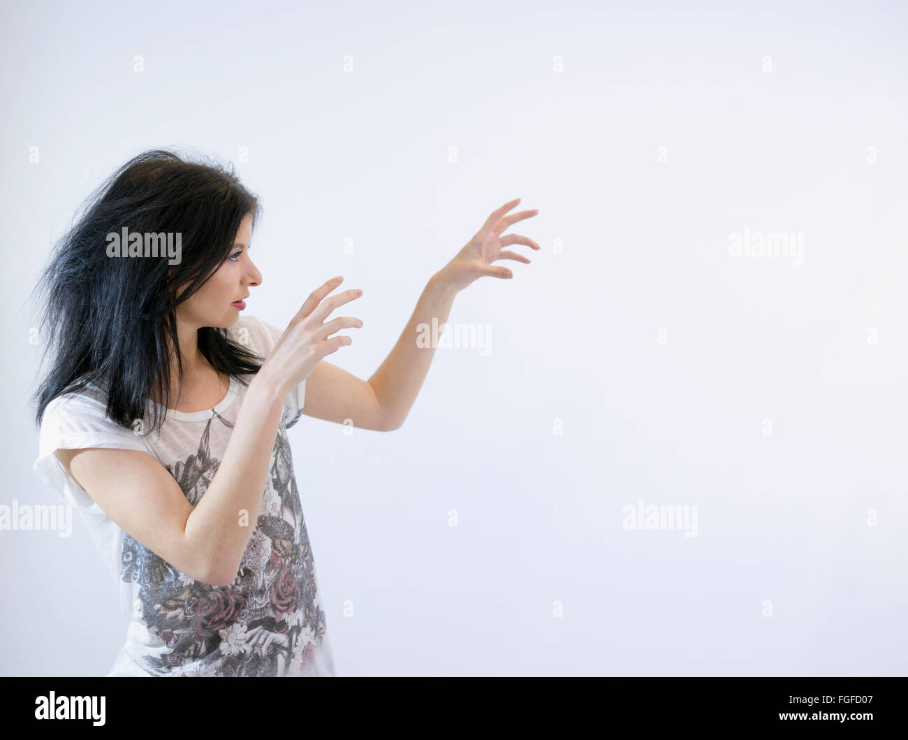 Mujer con largo cabello negro ilusionismo magia con sus manos en el aire Foto de stock