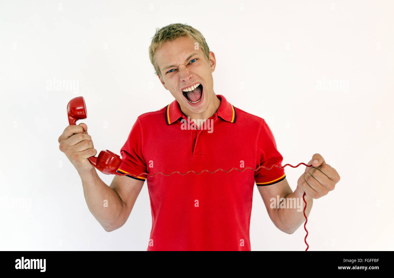 Hombre sujetando un teléfono rojo retro gritando Foto de stock