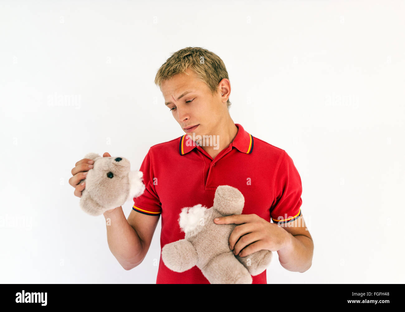 Hombre sujetando la cabeza y el cuerpo de un lindo oso de peluche juguetes buscando triste Foto de stock