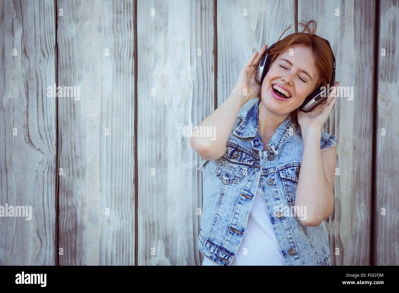 Sonriendo hipster mujer escuchando música a alto volumen a través de auriculares Foto de stock