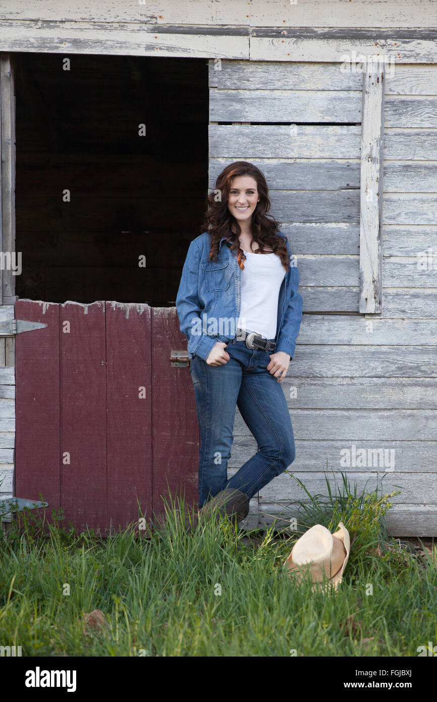 Hermosa morenita mujer vistiendo pantalones vaqueros y las botas en una  configuración de país Fotografía de stock - Alamy
