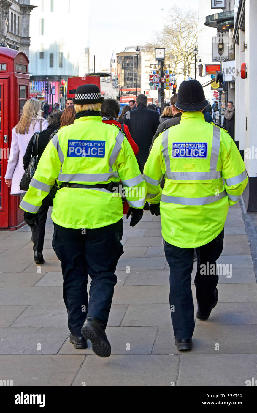 Vista posterior de la policía metropolitana funcionaria distintiva en la tapa izquierda y masculino tradicional oficial casco patrullando en West End, Londres Inglaterra Foto de stock