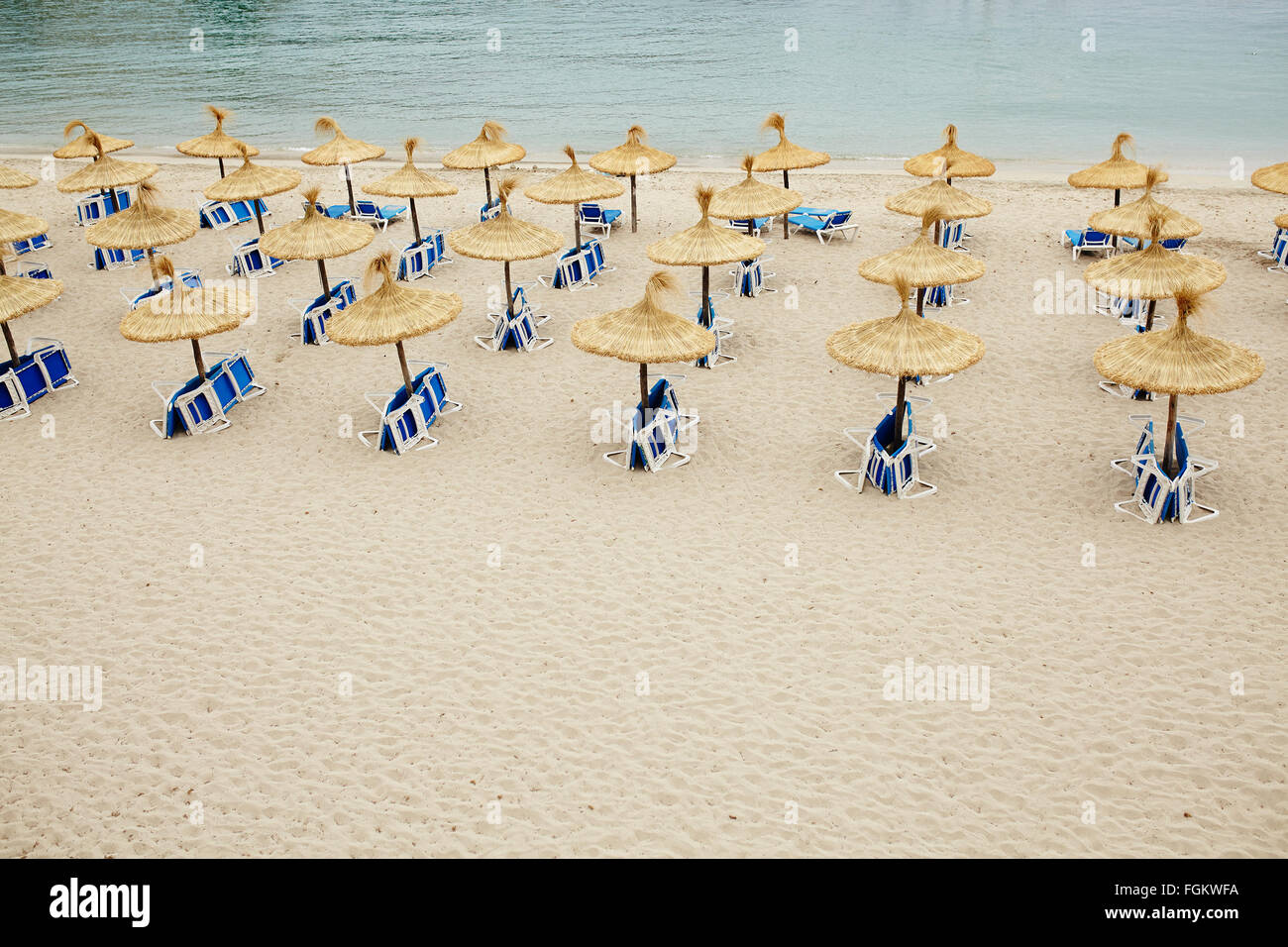 Grupo de sombrillas y tumbonas en la playa vacía. Foto de stock