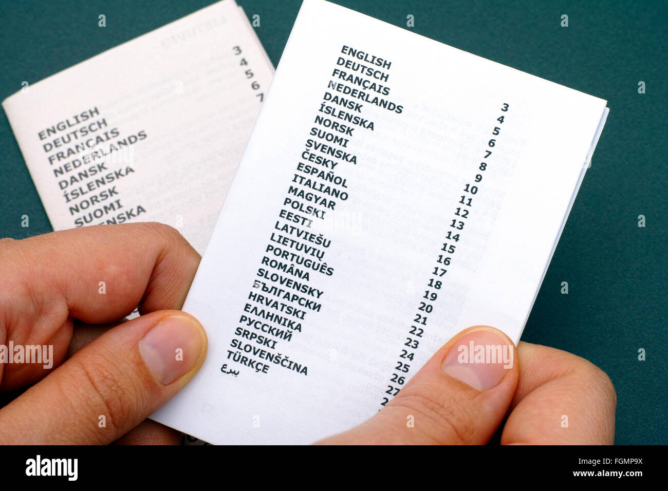 Folleto con la lista de idiomas en manos de la mujer. Fondo verde. Foto de stock
