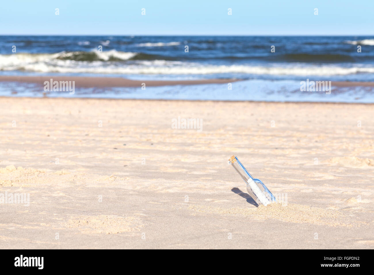 Botella con letra en una playa de poca profundidad de campo. Foto de stock