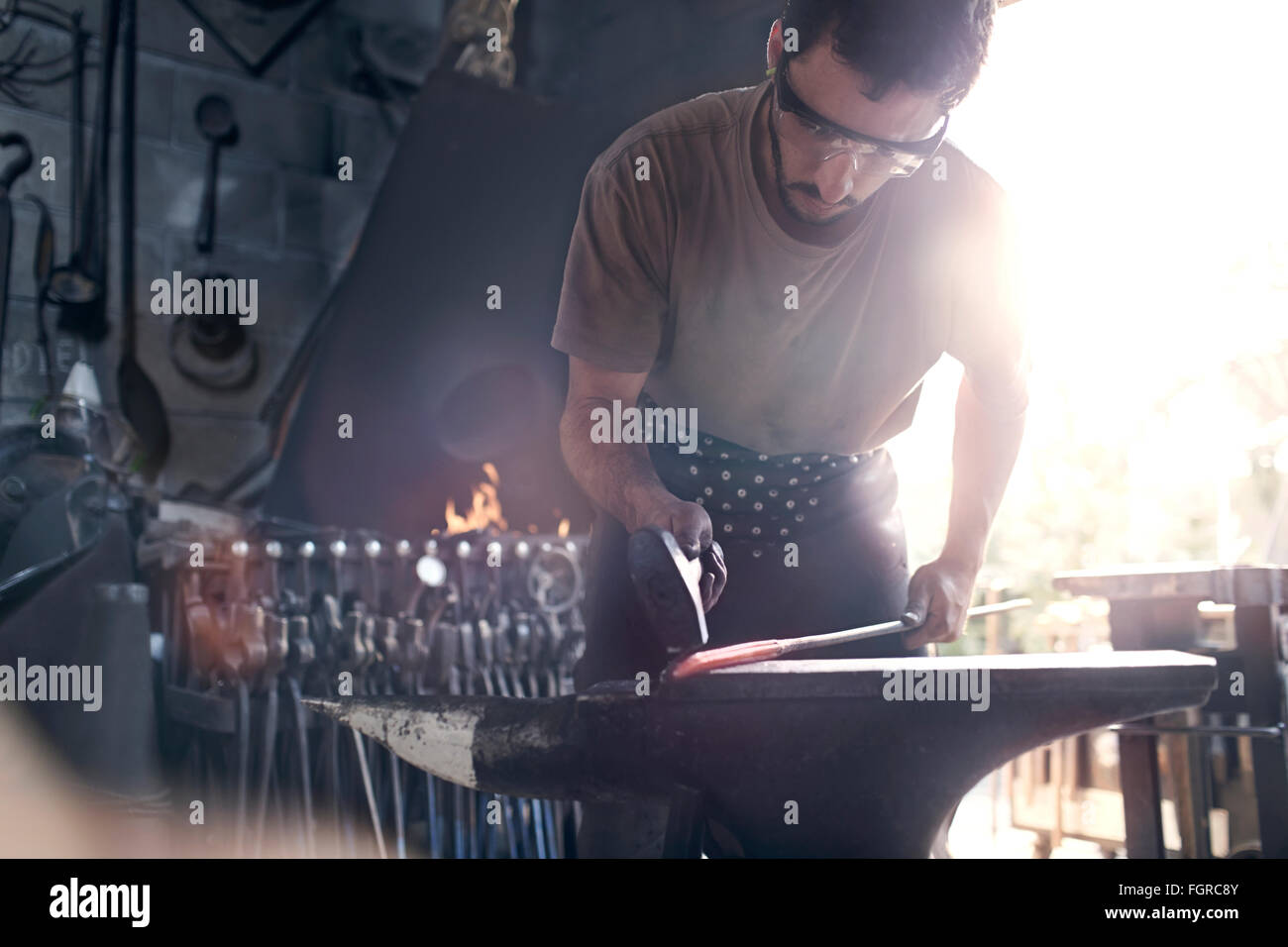 Herrero forja de hierro caliente en el yunque en Forge Foto de stock