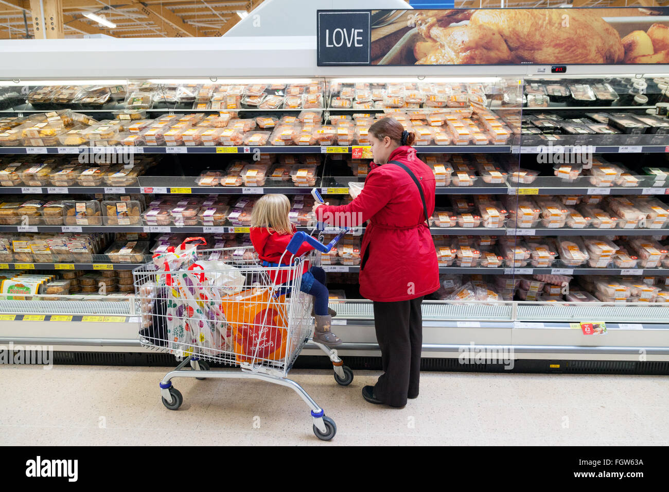 Una madre con su hijo en un carrito de compras en el supermercado, REINO UNIDO Foto de stock