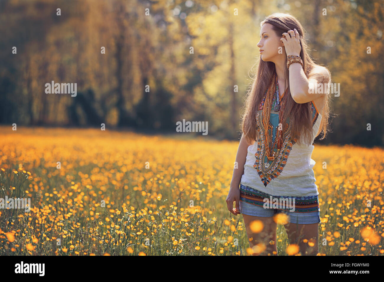 Hermosa mujer hippie en campo de flores . Colores de verano Foto de stock