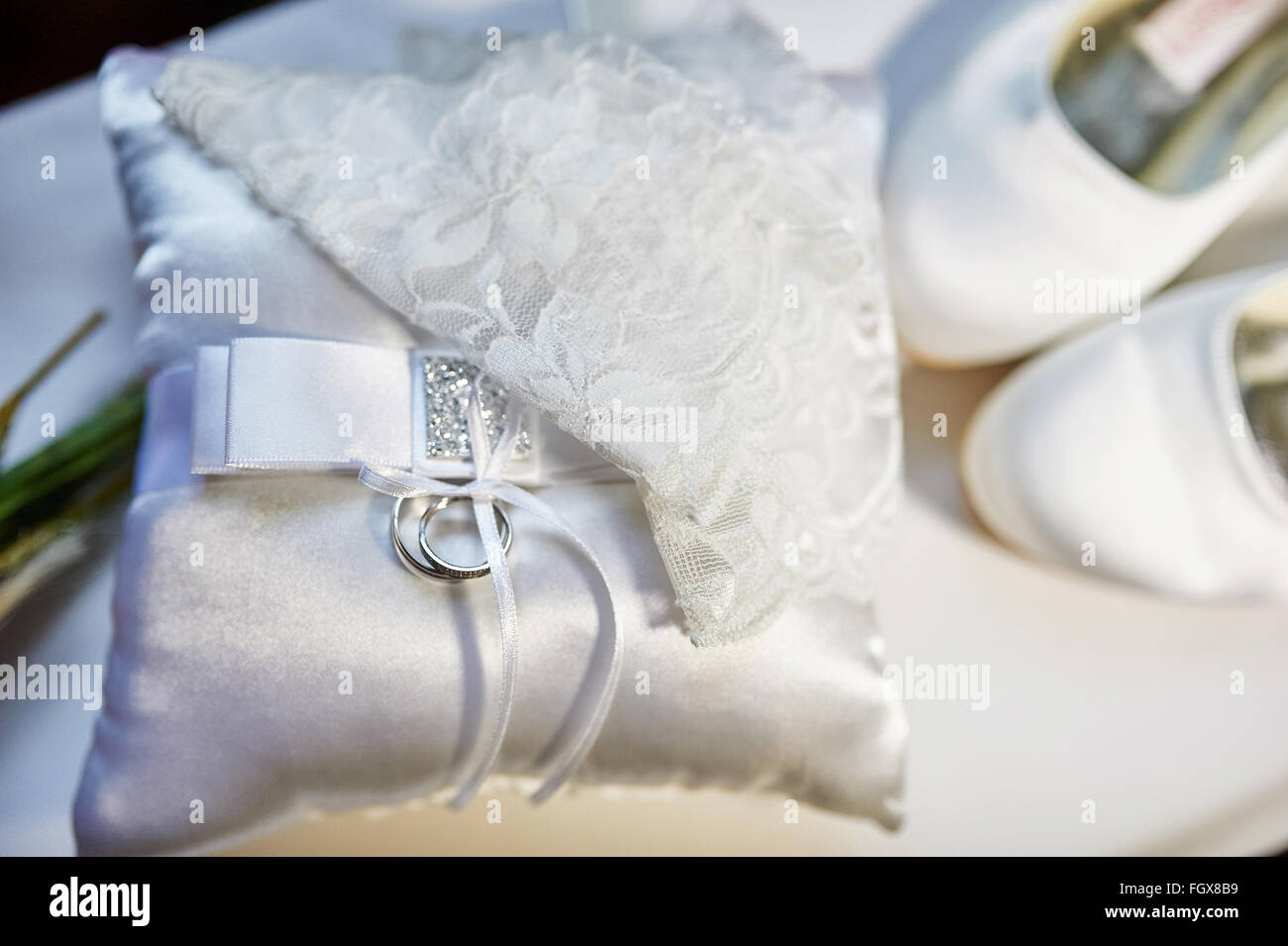 Los anillos de boda sobre un cojín, y la novia zapatos blancos Foto de stock