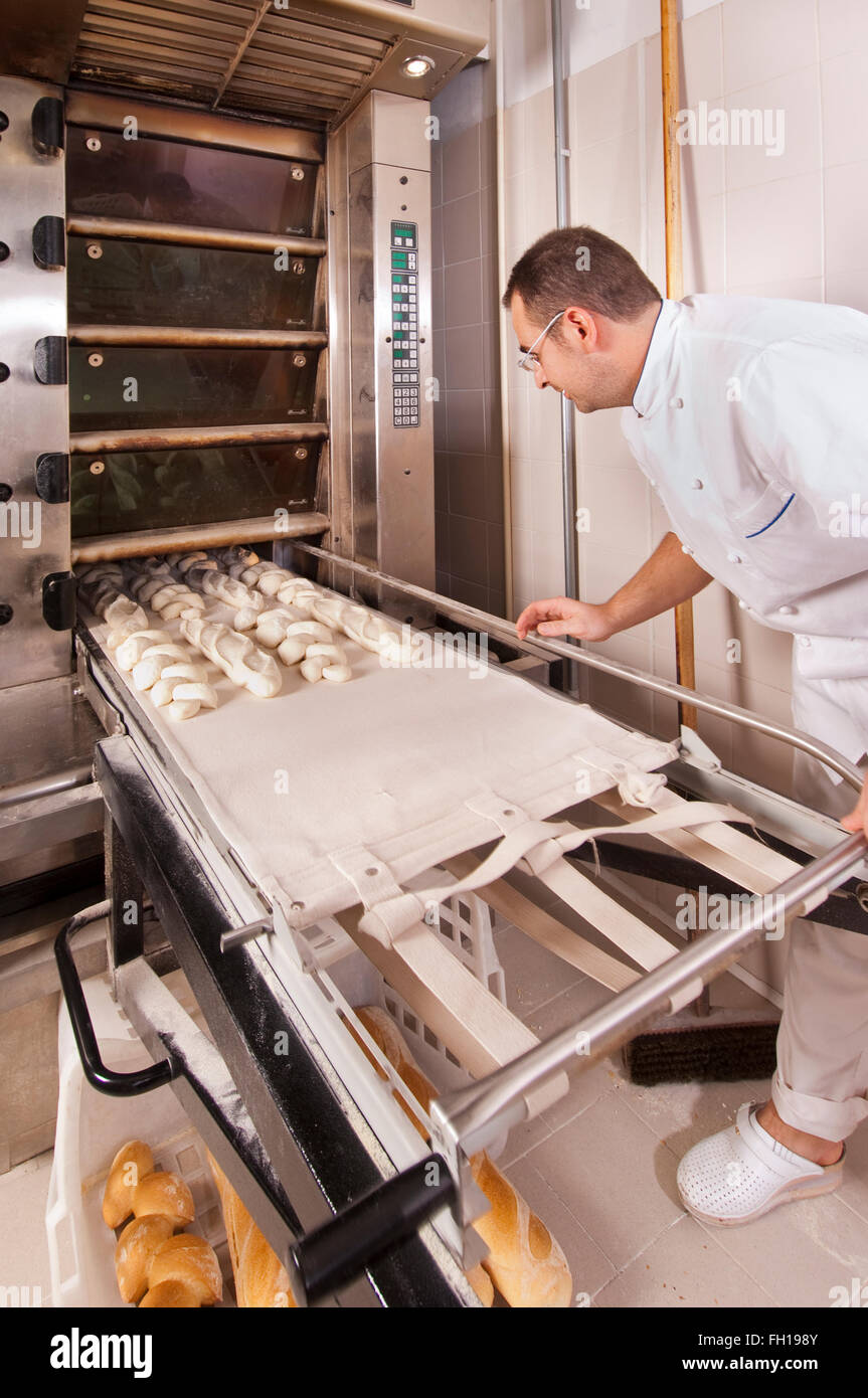 Baker, poner la masa de pan que se cuecen en el horno Fotografía de stock -  Alamy