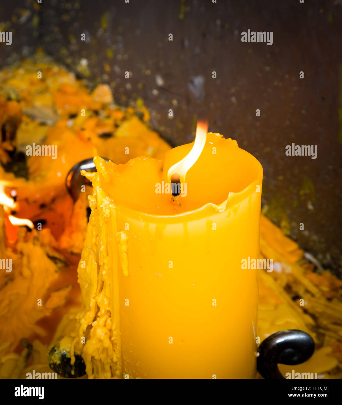 Velas grandes amarillas con fuego quemar en la parte superior y fundir la  cera al lado. Se coloca dentro de la cuchara de aceite Fotografía de stock  - Alamy