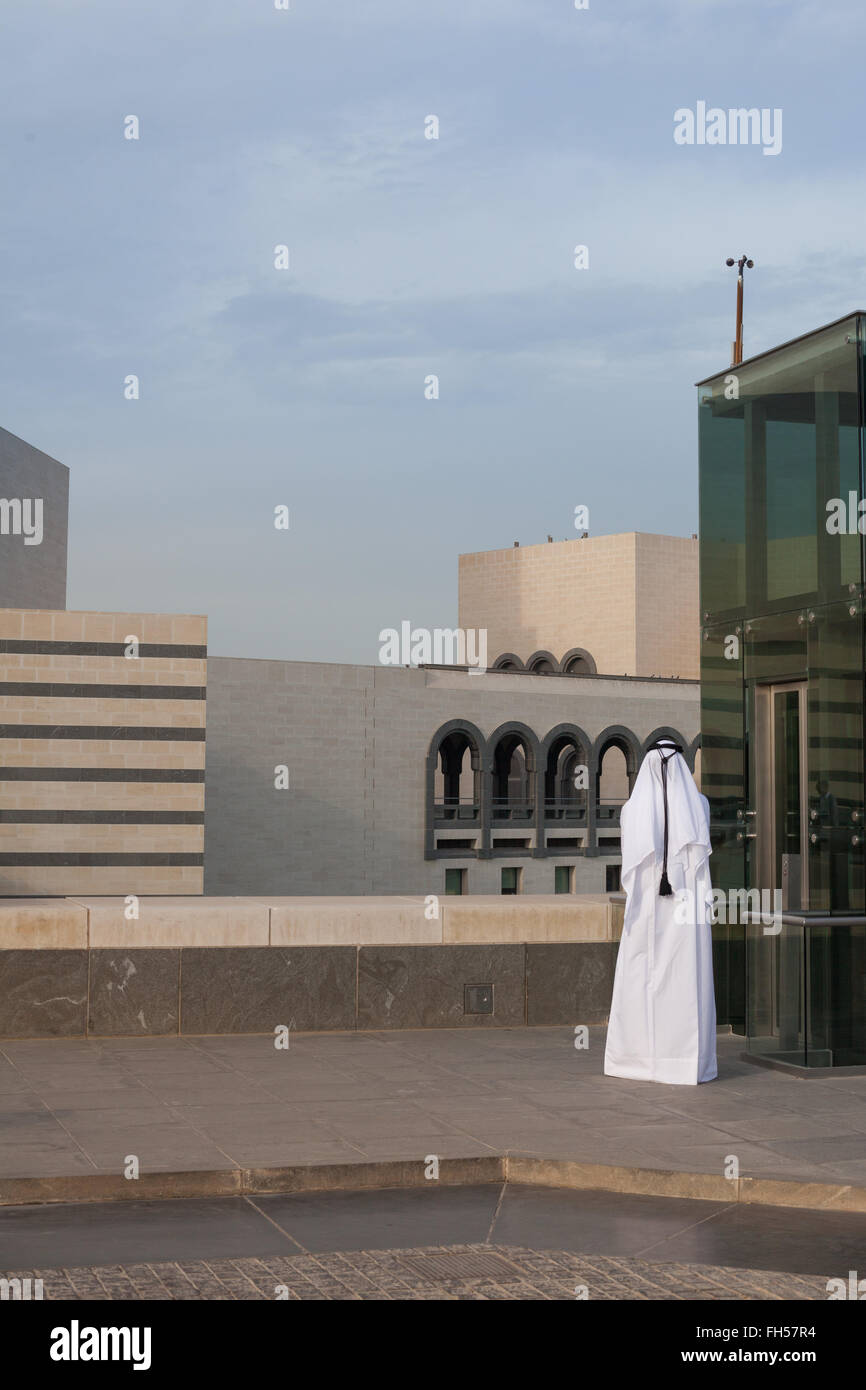 Hombre en traje tradicional árabe junto a un elevador fuera del Museo de Arte Islámico, Doha, Qatar Foto de stock