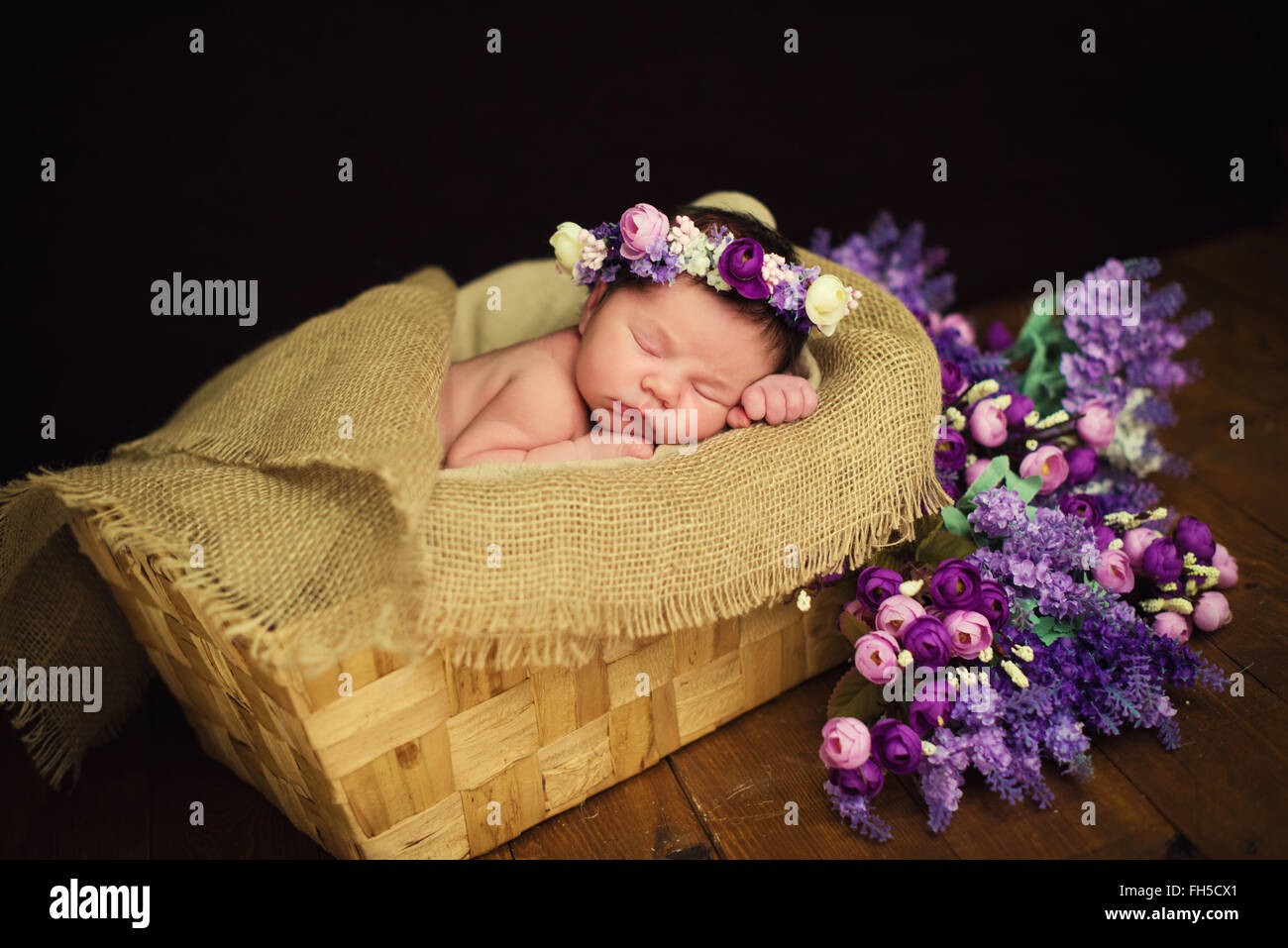 Hermoso bebé recién nacido chica con una corona púrpura duerme en una cesta  de mimbre Fotografía de stock - Alamy