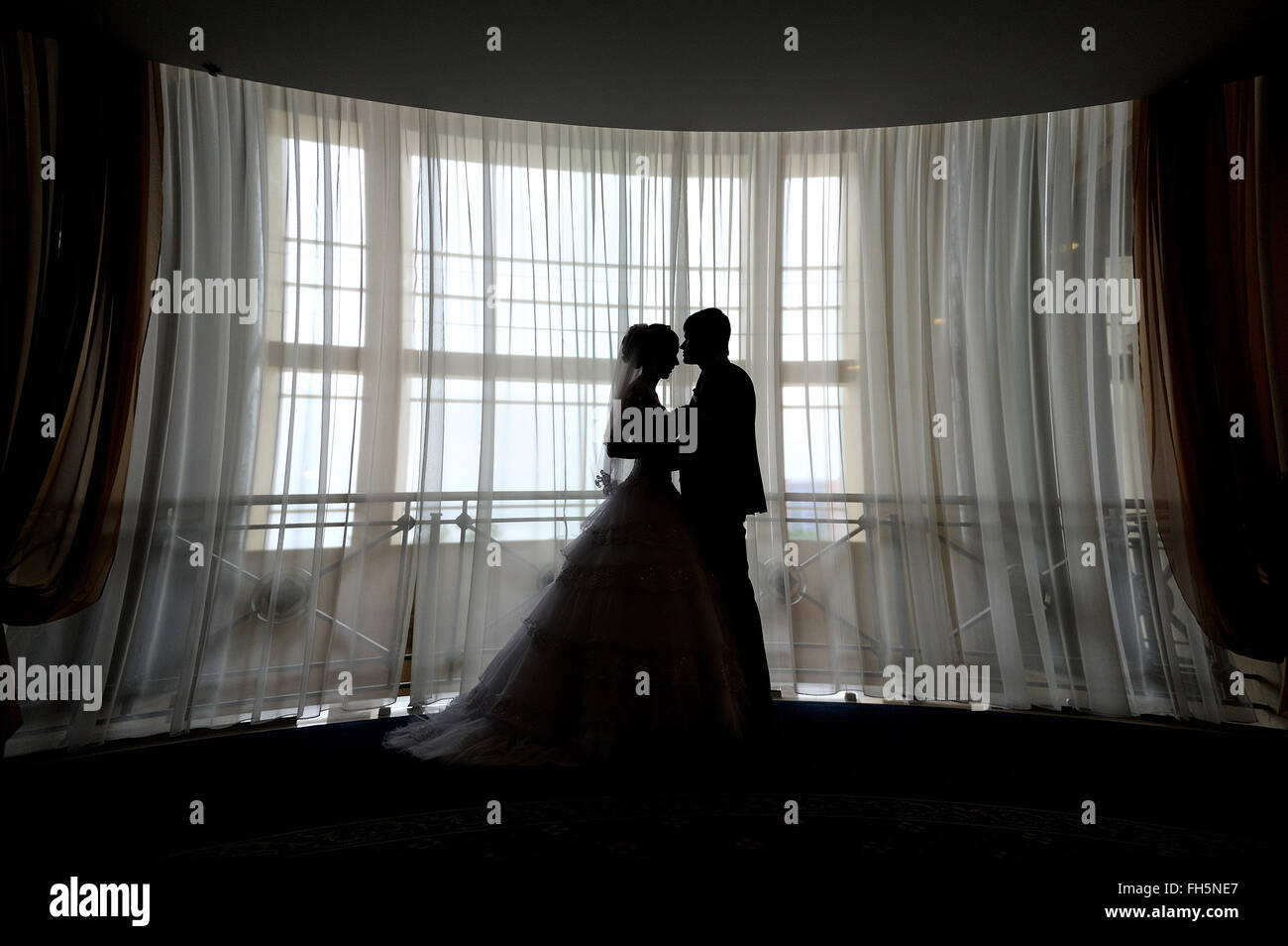 Silueta de la novia y el novio besarse en frente de la ventana estrecha Foto de stock