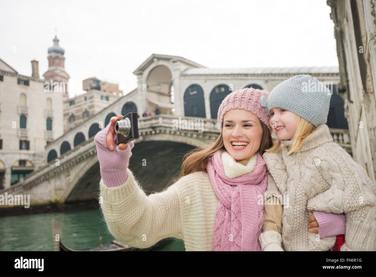 Familia moderna teniendo un receso de invierno para disfrutar de la aventura inspiradora en Venecia, Italia. Madre e hija tomando fotos mientras está de pie delante del Ponte di Rialto Foto de stock