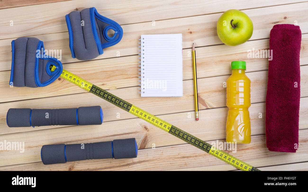 Concepto de Fitness con plan de entrenamiento . Pesas, pesas de muñeca,  toalla, Apple, cinta métrica, zumo de naranja y el portátil en el suelo  Fotografía de stock - Alamy