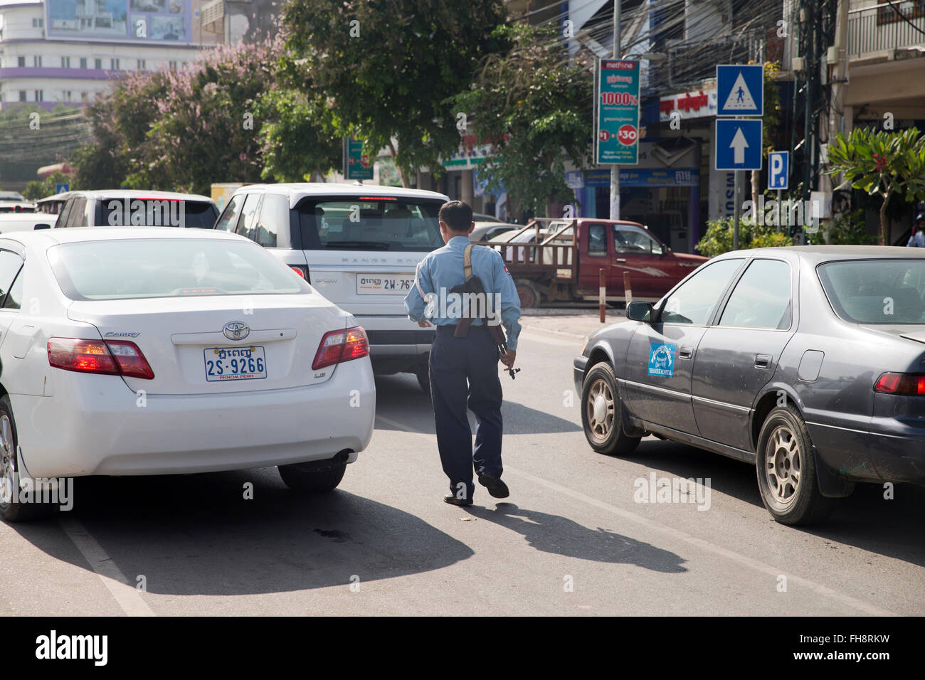 Cop armados con ametralladora organizando el tráfico en Phnom Penh, Camboya Foto de stock