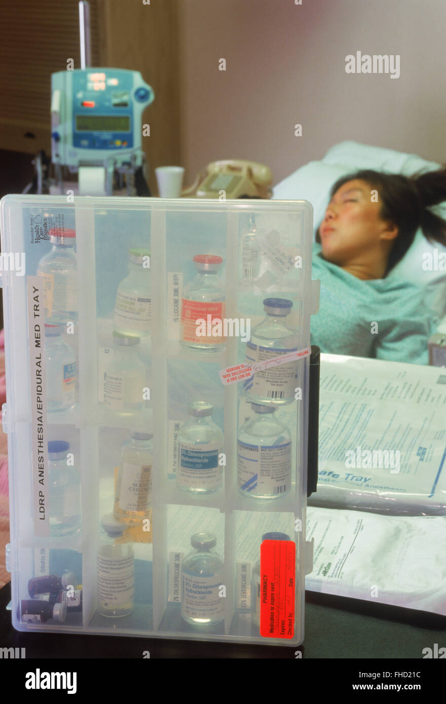 Mujer conectada a los tubos intravenosos en el hospital sala de recuperación con un menú de drogas Foto de stock