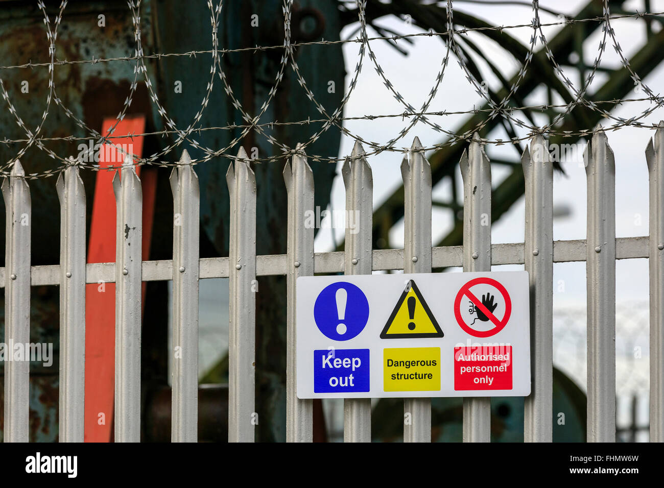 Valla de metal, alambre de espino y señales de peligro en el exterior de un polígono industrial cerrada, cerca de Glasgow, Escocia, Reino Unido Foto de stock