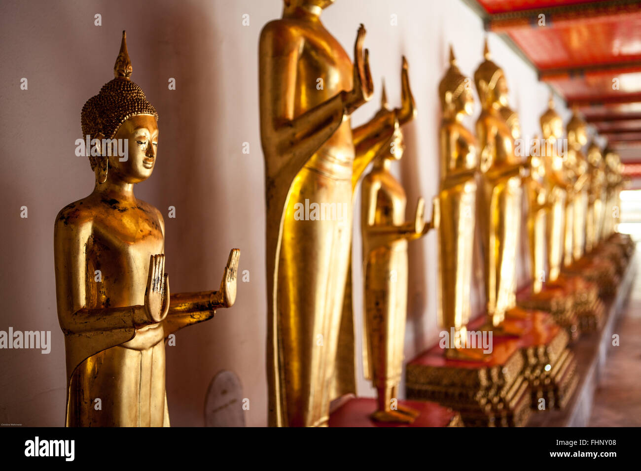 Una fila de pie budas de oro en Wat Pho, un famoso templo y atracción turística en Bangkok, Tailandia Foto de stock