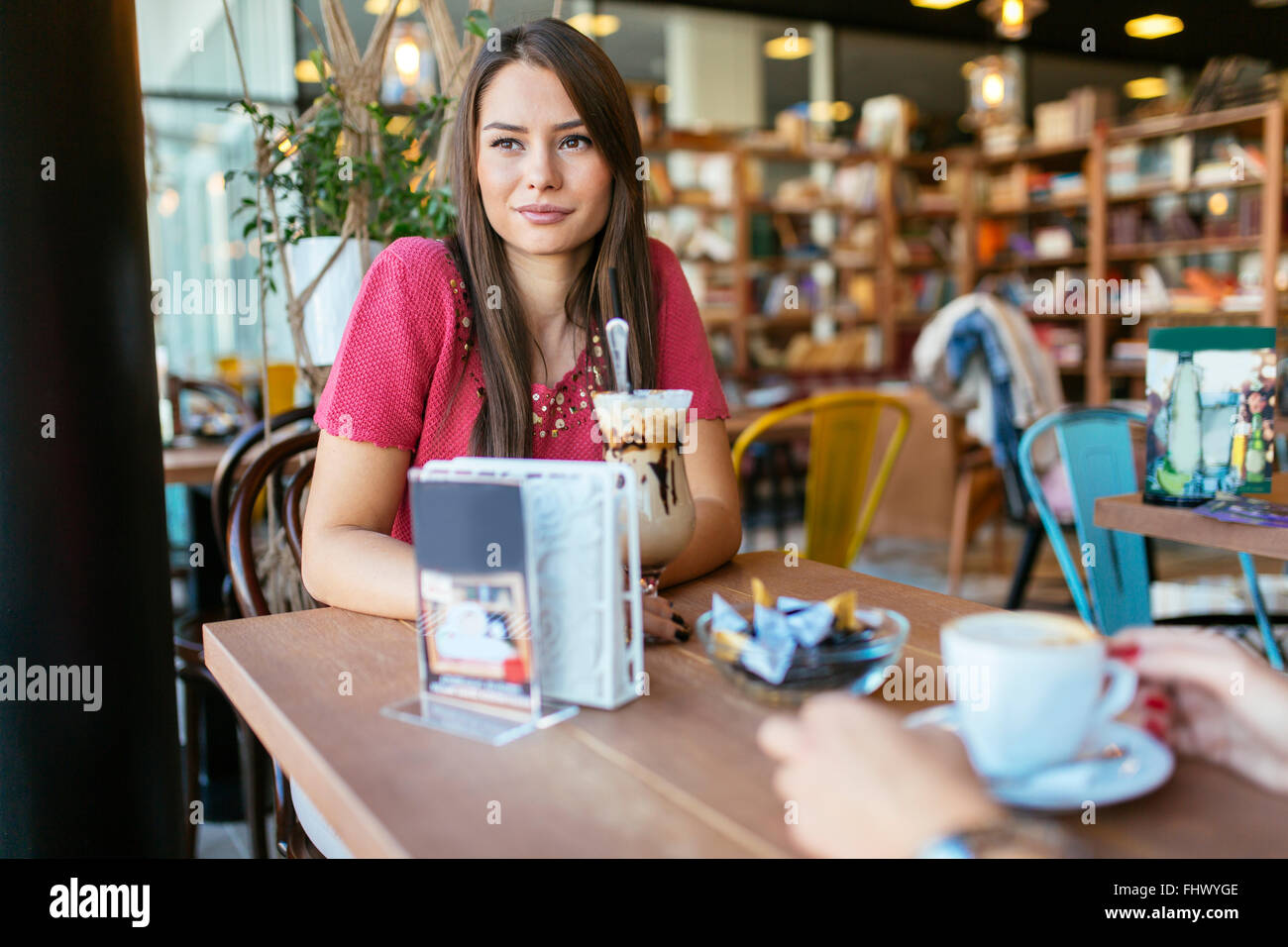 Bella mujer hablando con un amigo en el restaurante mientras bebiendo café Foto de stock