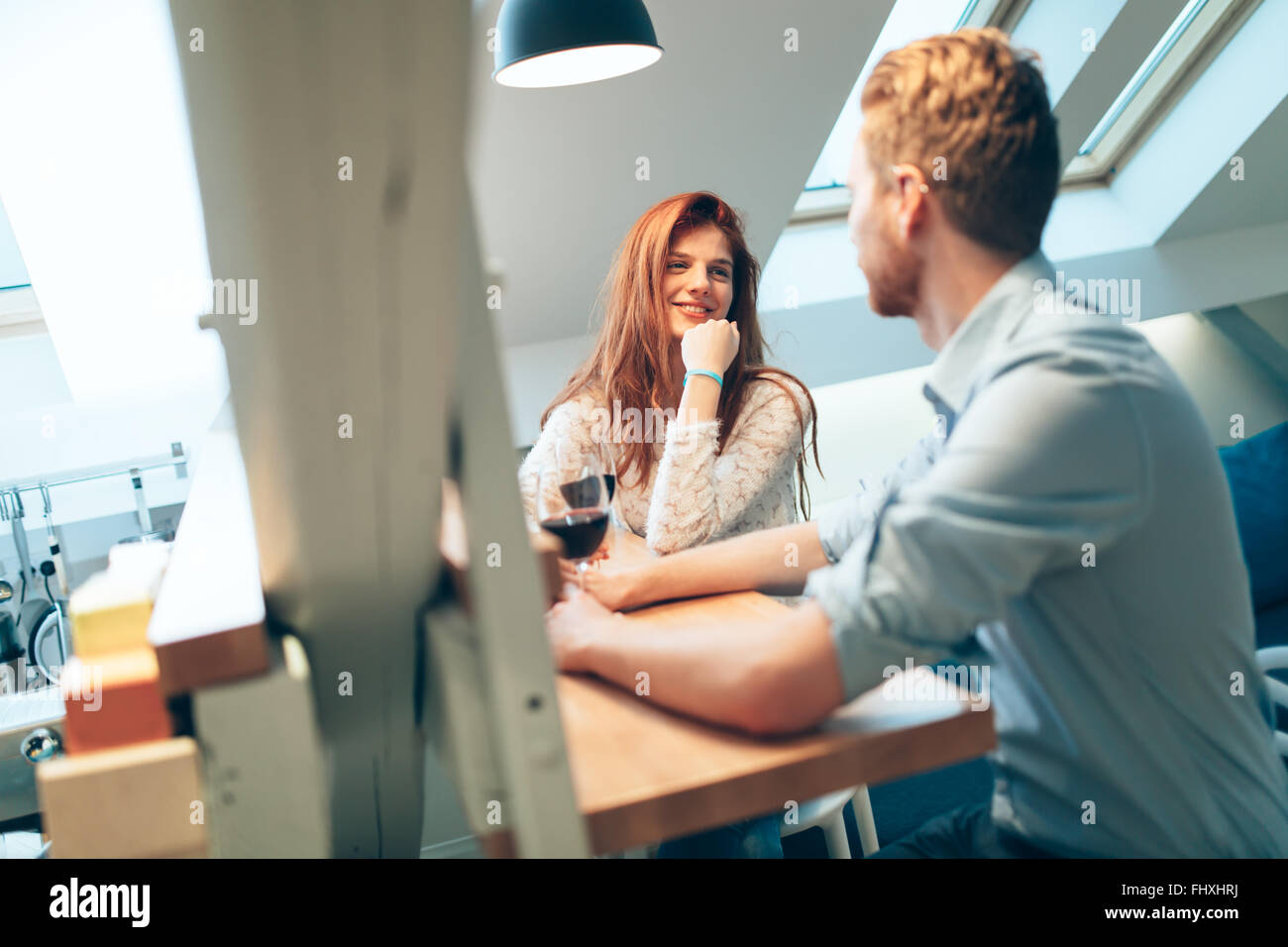 Hermosa pareja enamorada bebiendo vino en casa y hablar casualmente Foto de stock