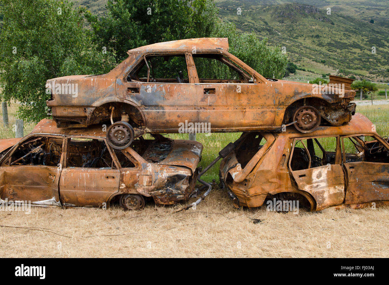 Una pila de tres automóviles oxidados, el cementerio de coches, Isla del Sur, Nueva Zelanda Foto de stock