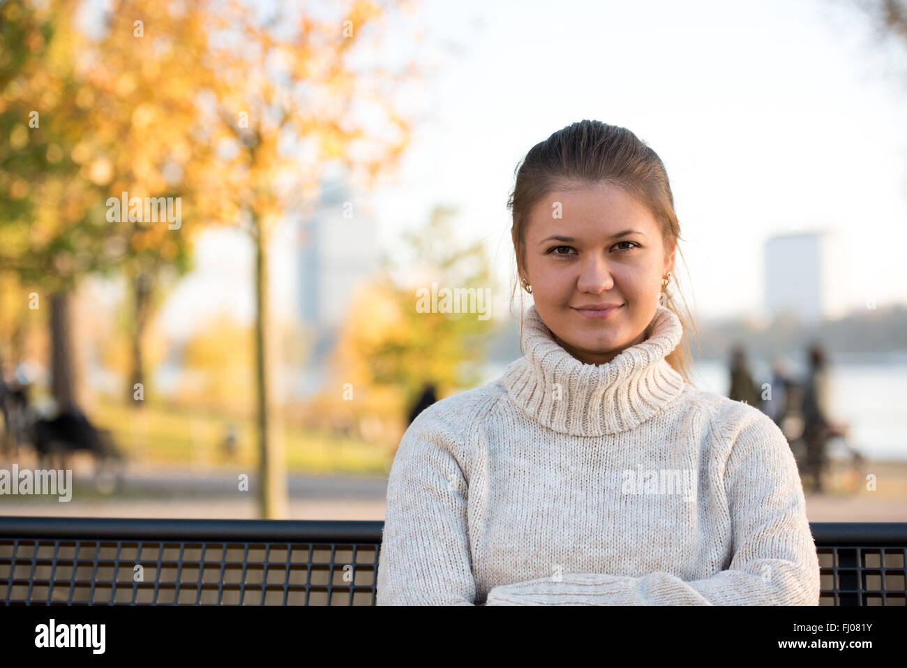 Joven en otoño sentado en el banco del parque Foto de stock