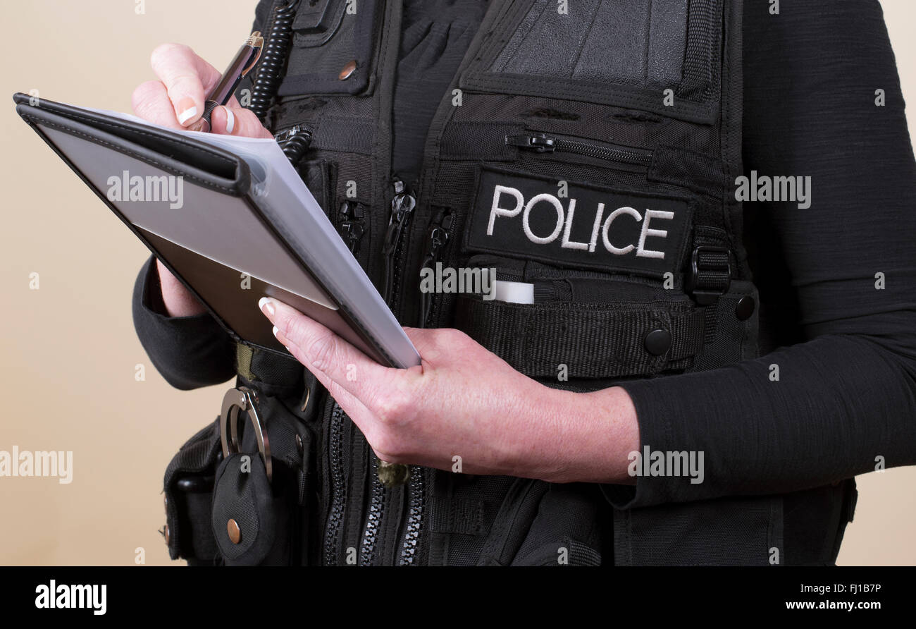 Oficial de policía vistiendo Tactical Vest escrito en un bloc de notas Foto de stock