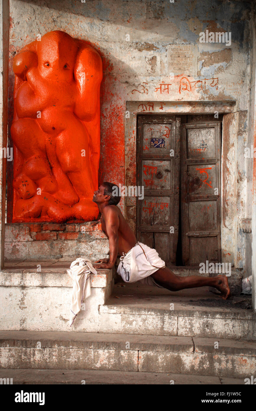 Hombre haciendo yoga cerca del templo de Hanuman en Varanasi Foto de stock