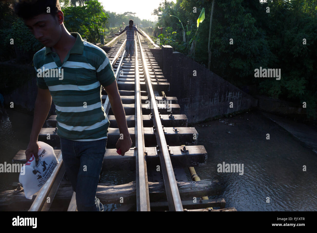Hombres caminan a lo largo de los rieles del tren / pistas de Sreemangal , Bangladesh Foto de stock