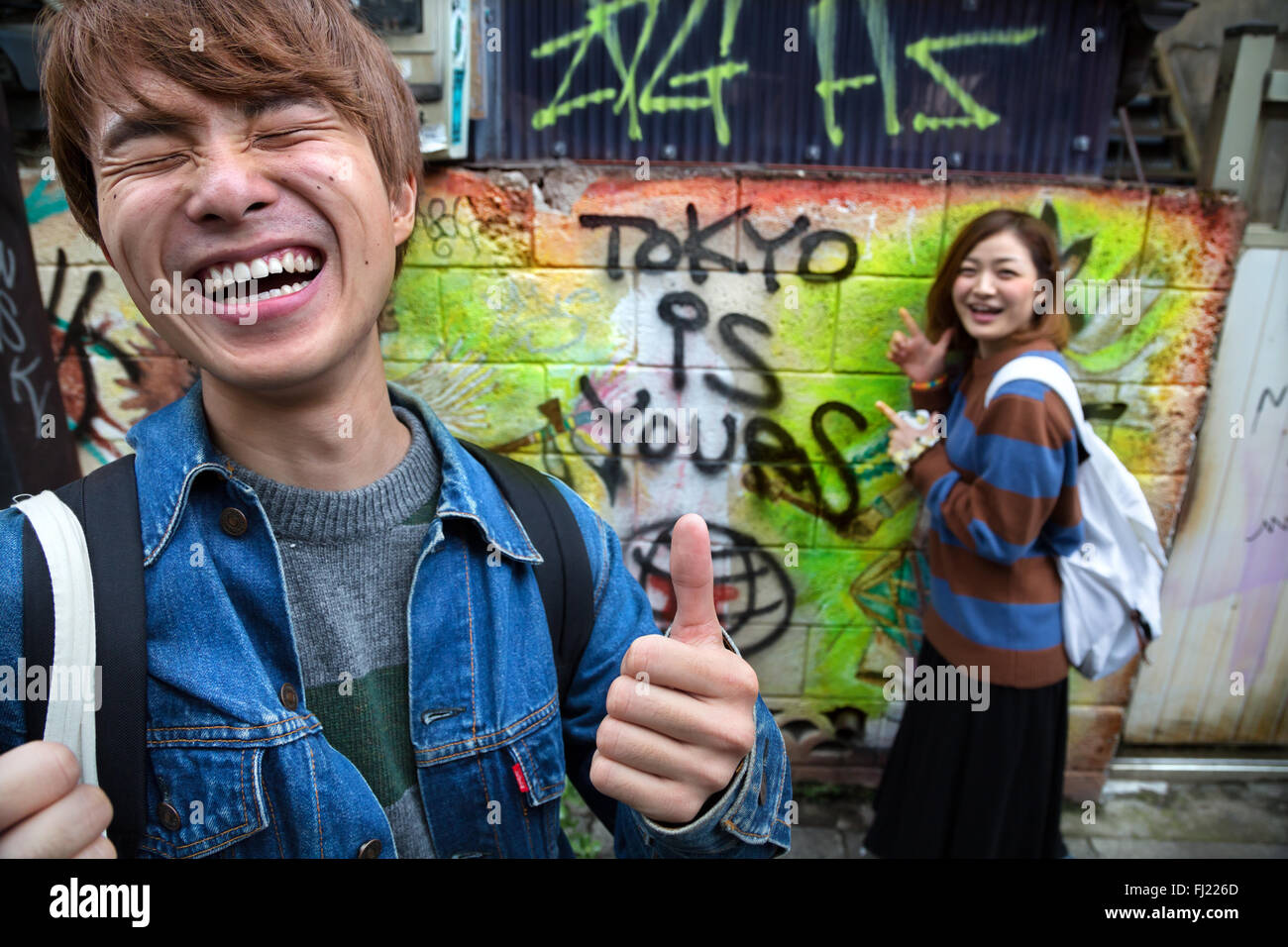 Dos jóvenes japoneses están divirtiéndose con escribir 'Tokyo es tuyo' en la pared - Bienvenido a Japón! Foto de stock