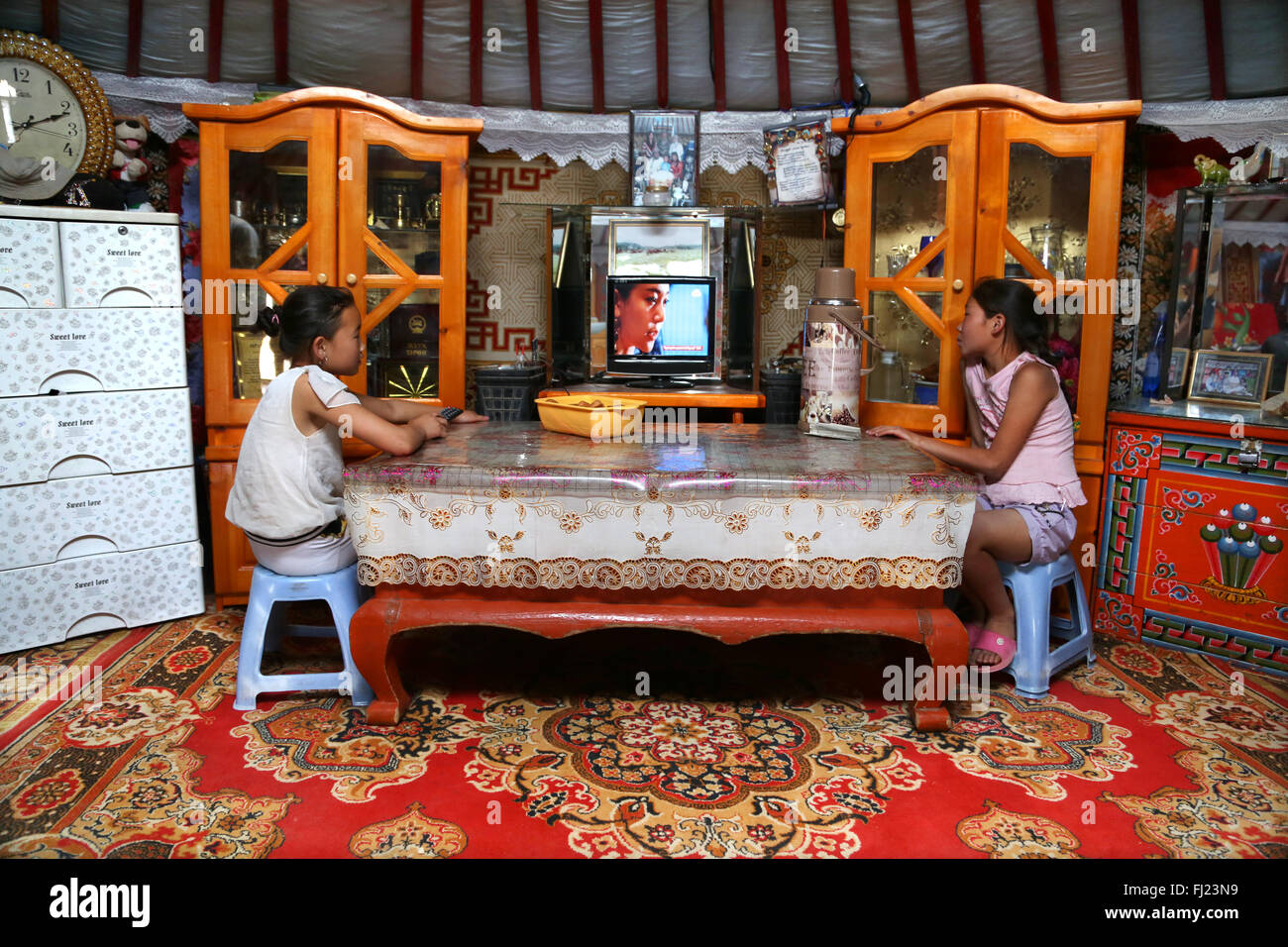 Dos muchachas jóvenes están viendo la televisión en un hogar tradicional llamado ger o Yurt en Mongolia Foto de stock