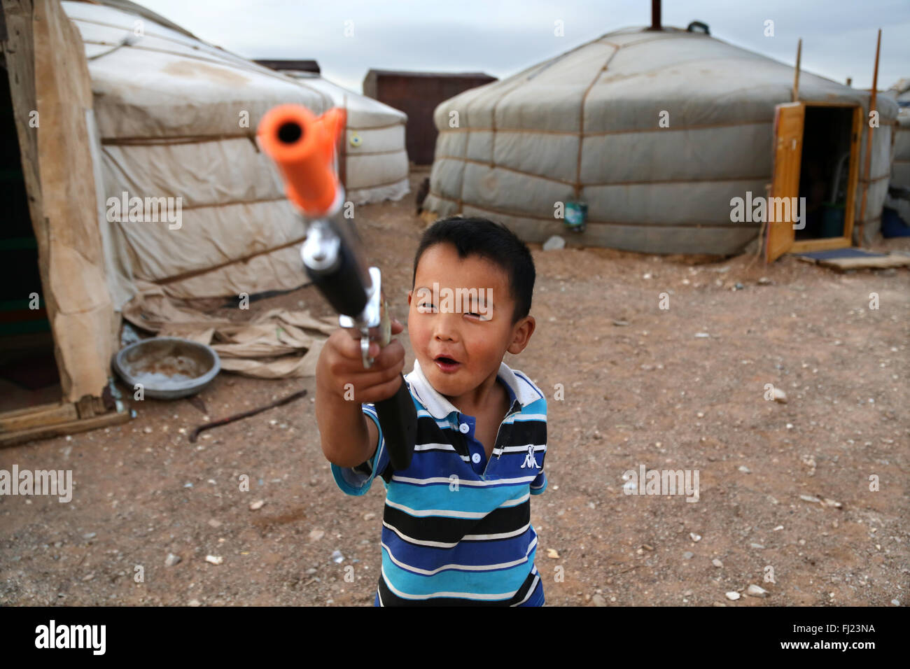Retrato de niño chico jugando con la pistola de plástico en la yurta ger camp en Mongolia Foto de stock