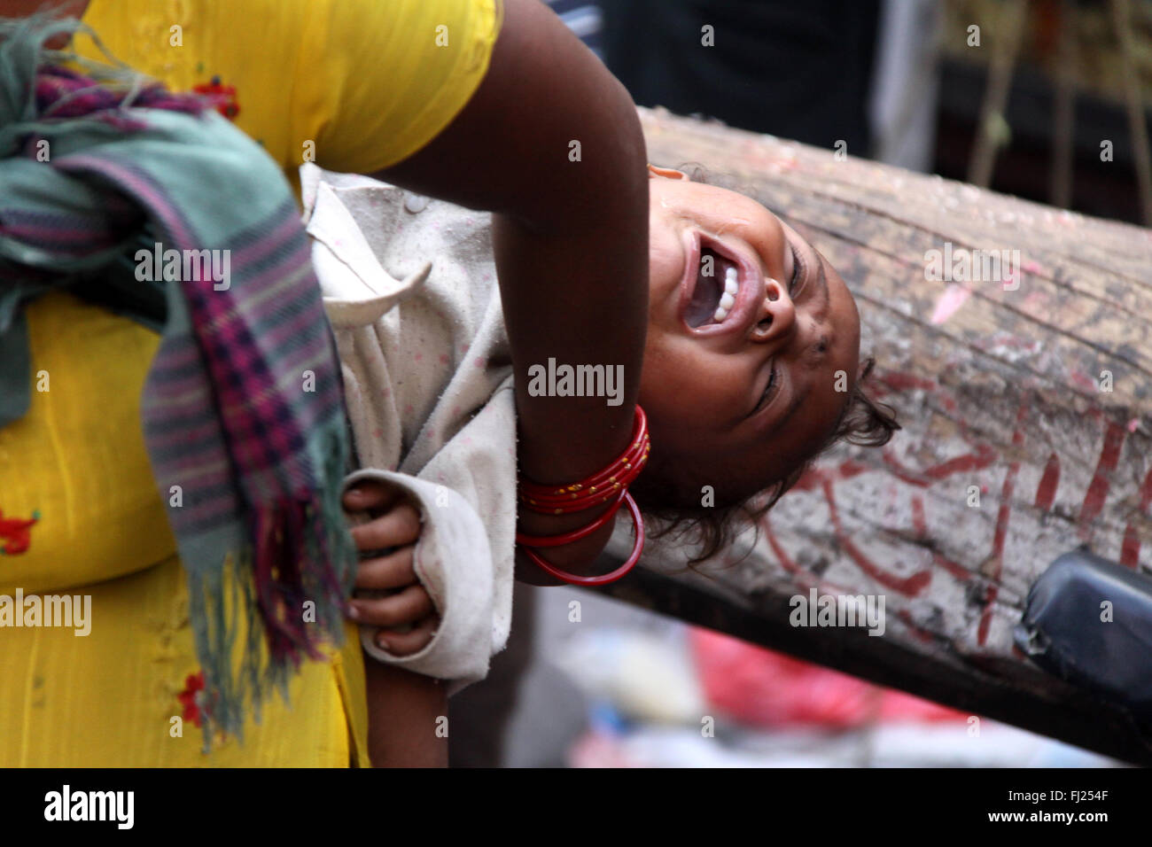 Bebé llorando en la parte de atrás de su madre en las calles de Patan, Nepal Foto de stock