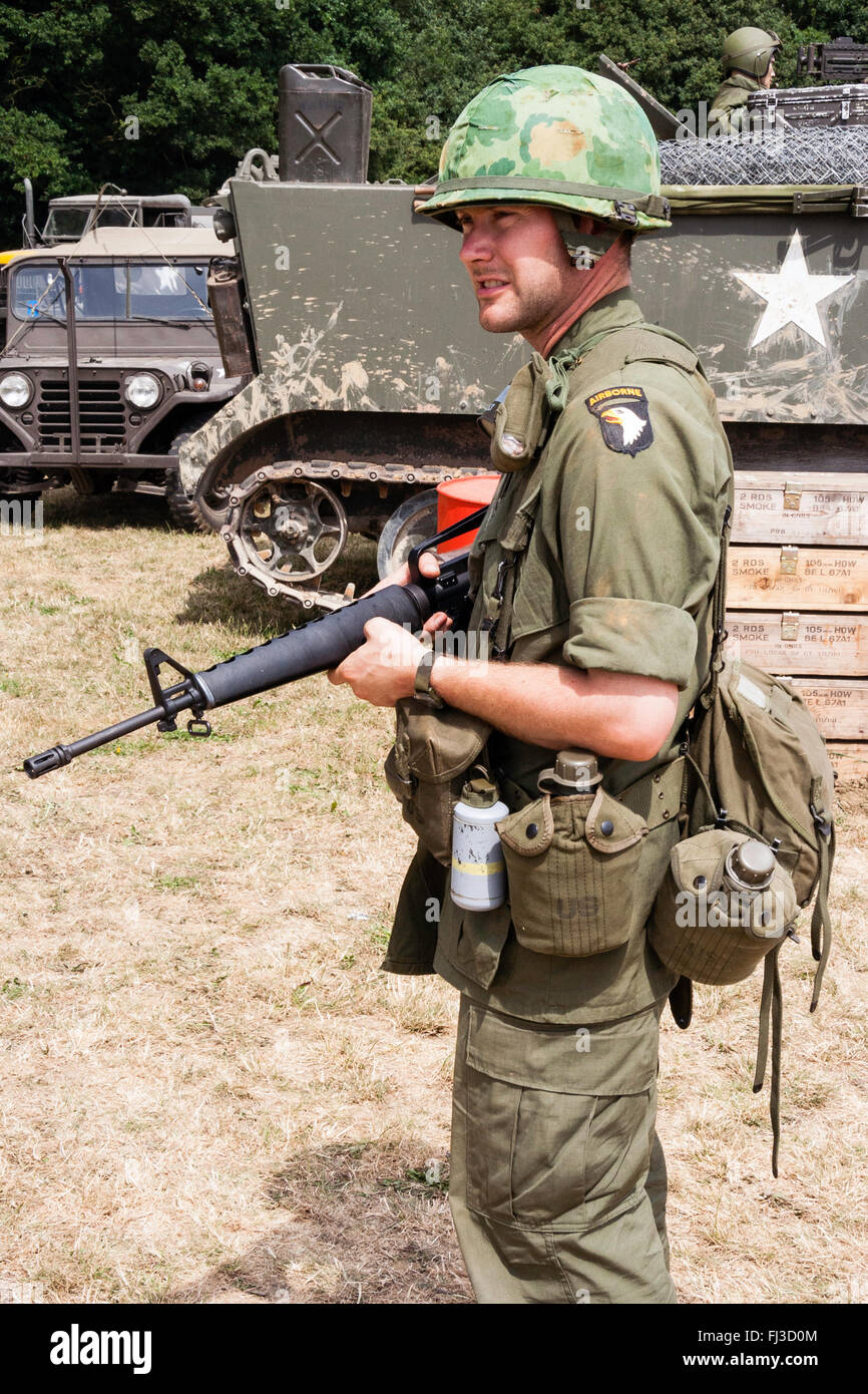 Período de la guerra de Vietnam la re-creación. Soldado americano en la  guardia de pie en el sol la celebración de fusil M16, y dos comedores  colgando de la correa Fotografía de