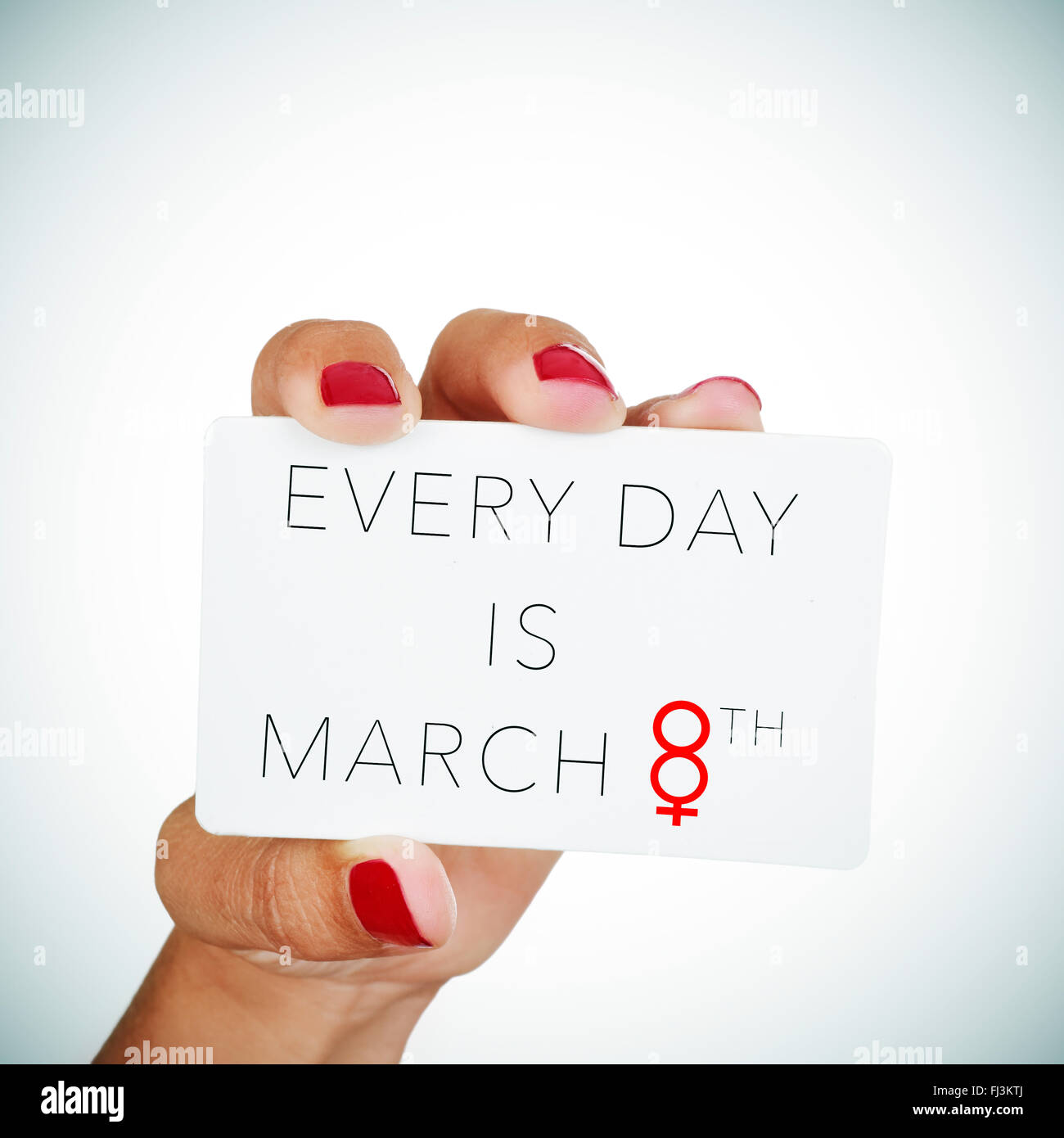 La mano de una mujer joven con clavos pulidos rojo sostiene un cartel con el texto cada día es el 8 de marzo, con el número 8 Foto de stock