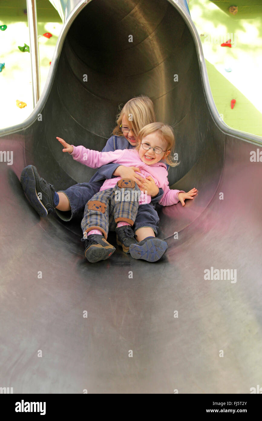 Chica, de 2,5 años de edad y un niño de 6 años de edad, divertirse en una diapositiva, Alemania Foto de stock