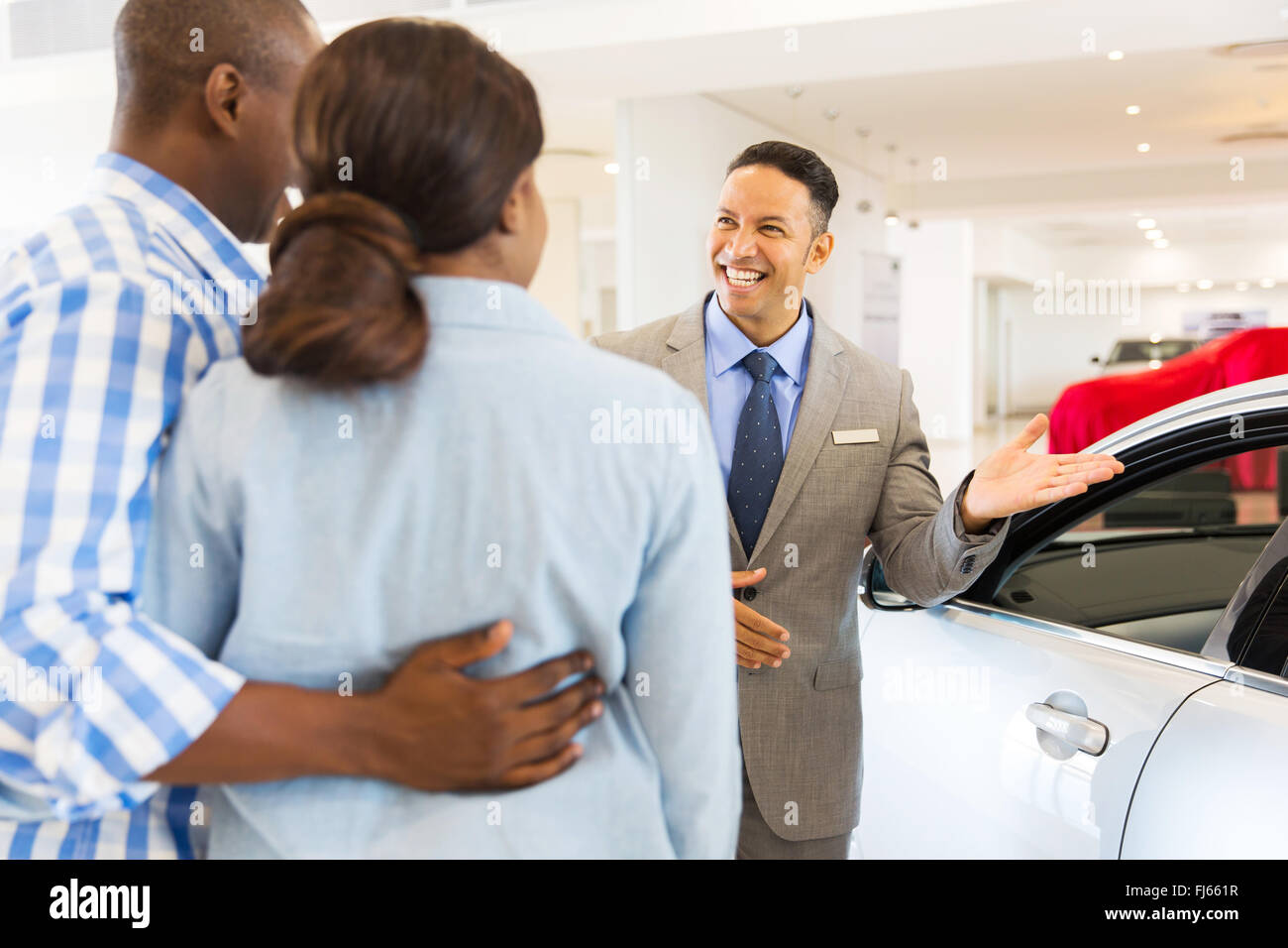 Concesionario de automóviles amigable mostrando coche nuevo para clientes Foto de stock