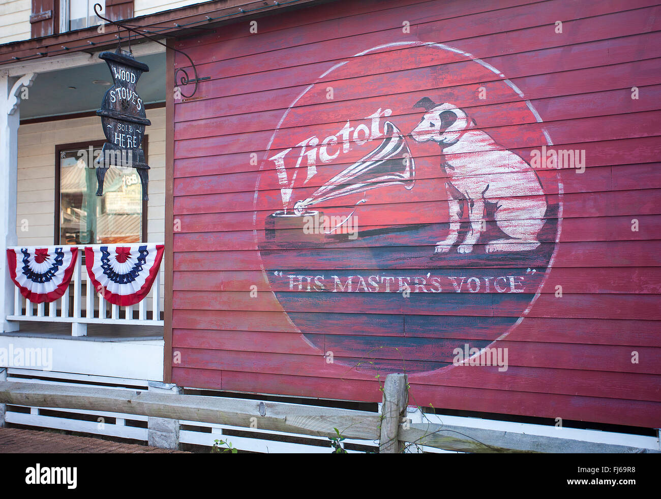 Imágenes de un signo y el metal pintado 'Victor' logo y una valla con bunting en una tienda que vende estufas de leña en San Agustín, Florida, EE.UU. Foto de stock